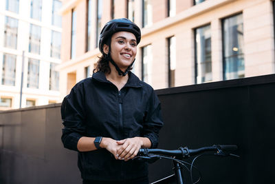 Young woman standing by bicycle