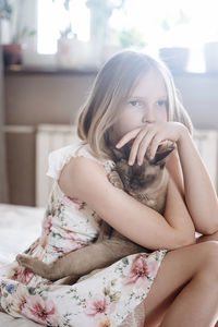 Young woman sitting on bed at home