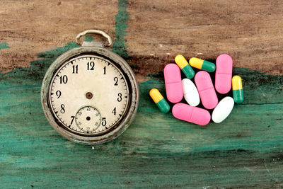 Directly above shot of medicines and stopwatch on wooden table
