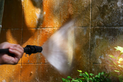 Hand spraying water through garden hose