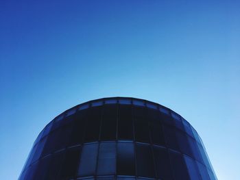 Low angle view of glass building against clear blue sky