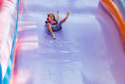 Happy little girl having lots of fun on a jumping castle during sliding.