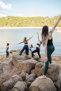 Women on rocks at shore against sky