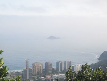 Scenic view of sea by buildings against sky