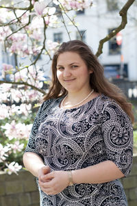 Portrait of a beautiful plump caucasian confident woman in magnolia flowers