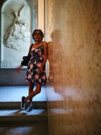 Full length portrait of woman standing against wall