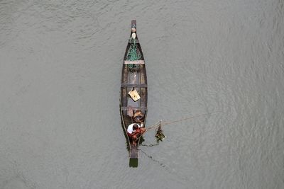 High angle view of man fishing while sitting on boat in lake