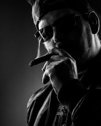 Portrait of man smoking cigar on black background