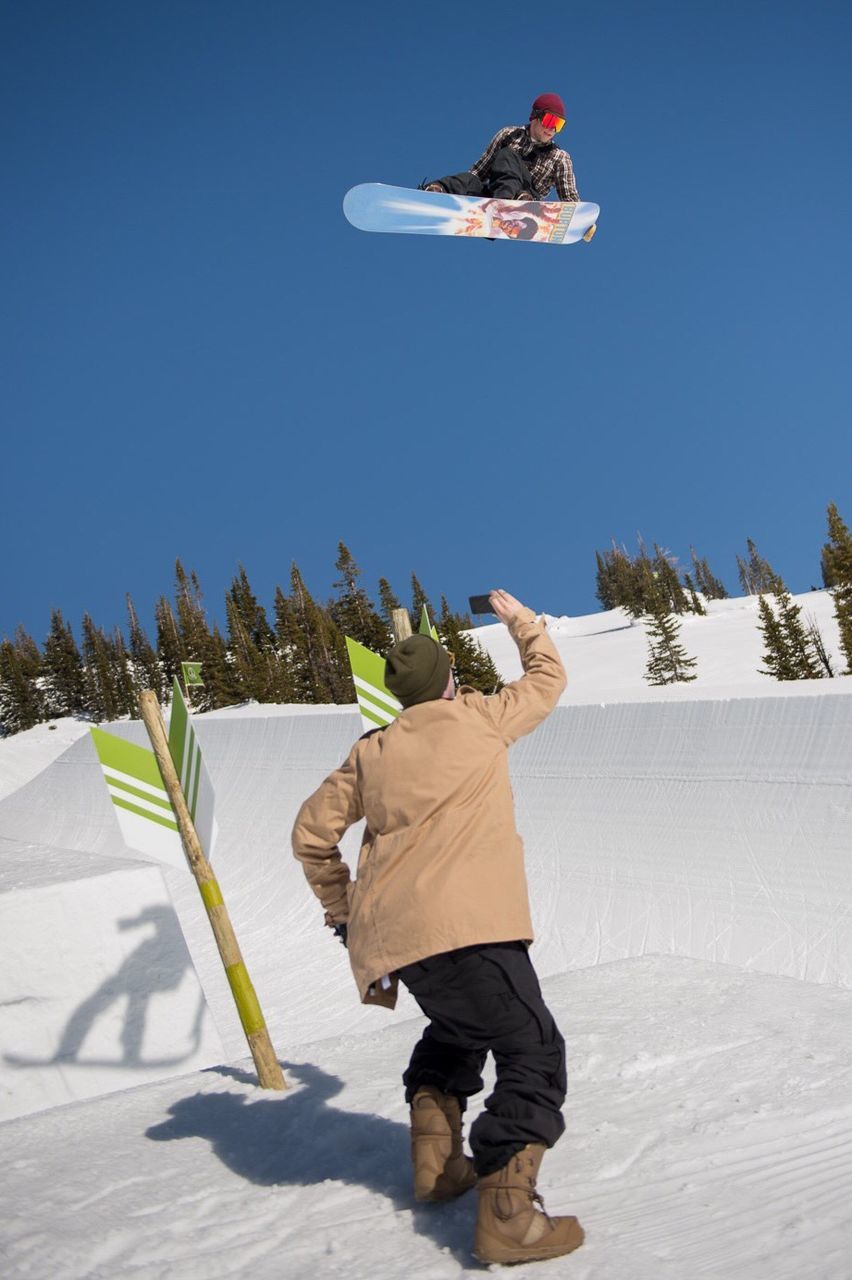 full length, lifestyles, leisure activity, clear sky, casual clothing, mid-air, copy space, men, rear view, sunlight, skill, extreme sports, sport, holding, day, blue, shadow, enjoyment