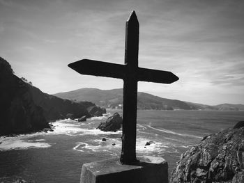 Cross on shore against sky