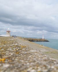 Lighthouse by sea against sky