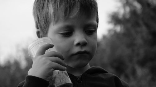 Close-up of boy holding camera against sky