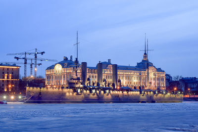 River by illuminated city against sky at dusk