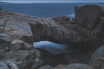 Rock formation by sea against sky