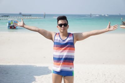 Man with arms outstretched standing at beach