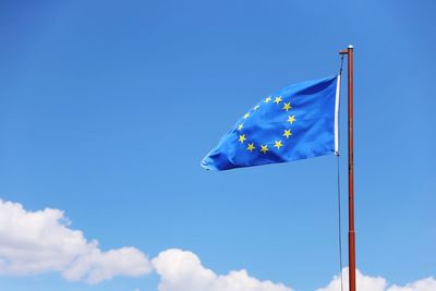 Low angle view of flag against blue sky