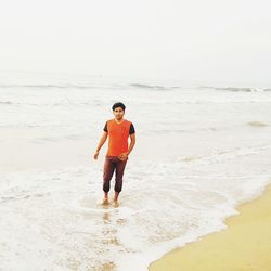 Young man standing on shore at beach