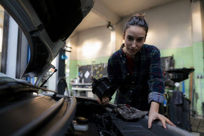 Female mechanic repairing car at workshop