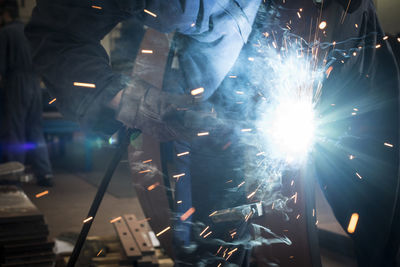 Midsection of welder welding metal in factory