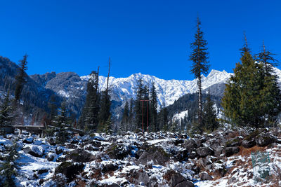 Scenic view of snow covered mountains against clear blue sky