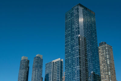 Low angle view of modern buildings against clear blue sky