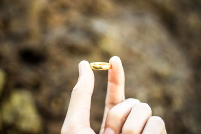 Cropped hand holding gold ring