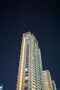 Low angle view of illuminated buildings against sky at night