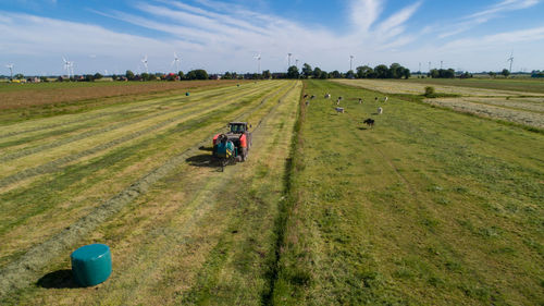 Black tractor with a red straw chamber press during the straw harvest on a mown field