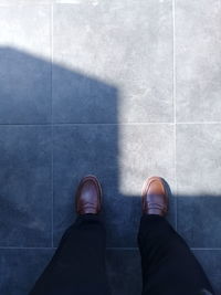 Low section of man standing on tiled floor