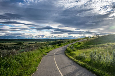 Road amidst field against sky