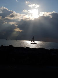 Silhouette sailboat in sea against sky during sunset