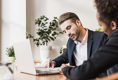 Young businessman and woman using laptop