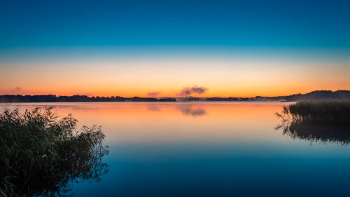 Scenic view of lake against clear sky at sunset