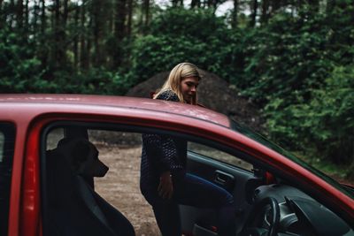 Side view of woman sitting in car at forest