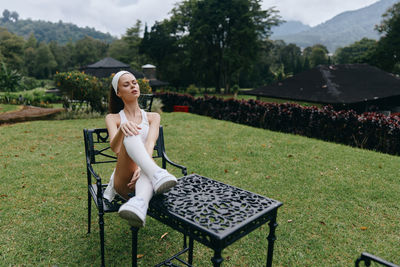 Side view of young woman sitting on field