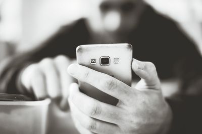 Close-up of man using smart phone at home