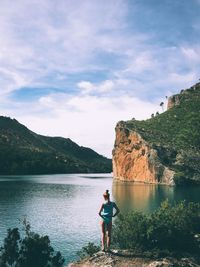 Rear view full length of woman standing at lakeshore