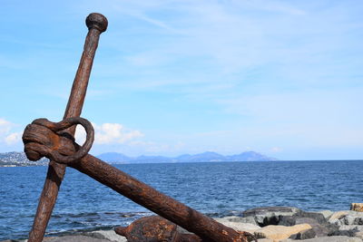 Close-up of rusty metal by sea against sky