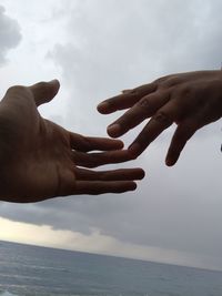 Midsection of man with hands against sea against sky