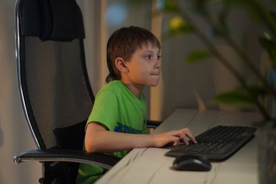 Cute caucasian boy playing video game at desktop computer at home