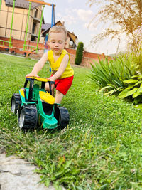 A little cute boy of one and a half years plays with toy tractor outdoor. adorable toddler playing 