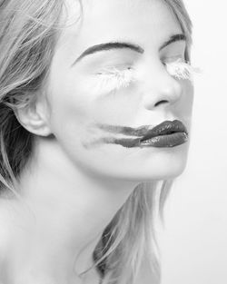 Beautiful woman with smudge lipstick and false eyelashes against white background