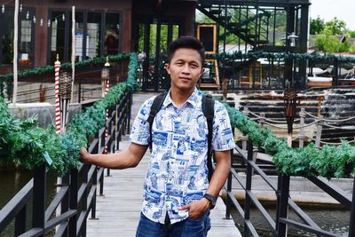 Portrait of young man standing on footbridge