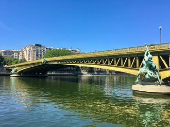 Arch bridge over river against clear blue sky