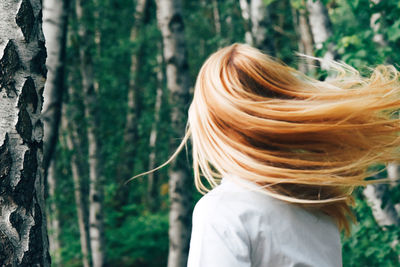 Rear view of woman against trees in forest