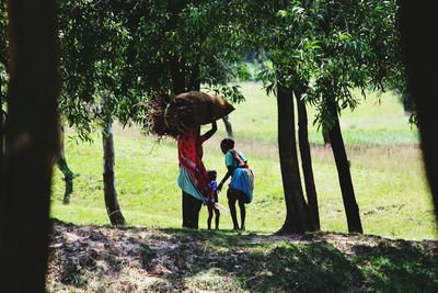 Rear view of mother and daughter on field