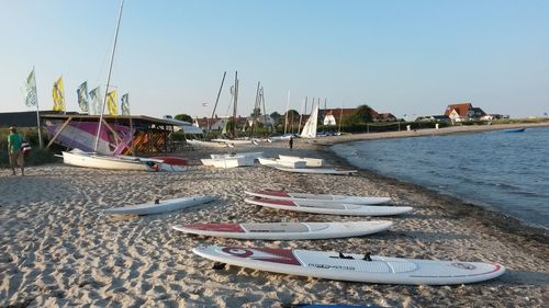 Boats moored on beach against clear sky