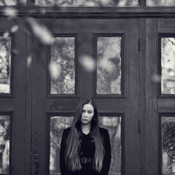 Portrait of woman standing against window