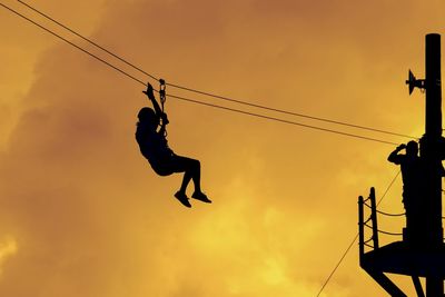 Low angle view of silhouette crane against sky during sunset