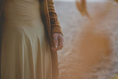 Midsection of woman holding umbrella standing on land